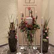 Urne mit üppigem Blumenschmuck in Rosa- und Naturtönen, Kerzen und floralen Gestecken – Trauerfloristik Gärtnerei Reinwald Heilbronn