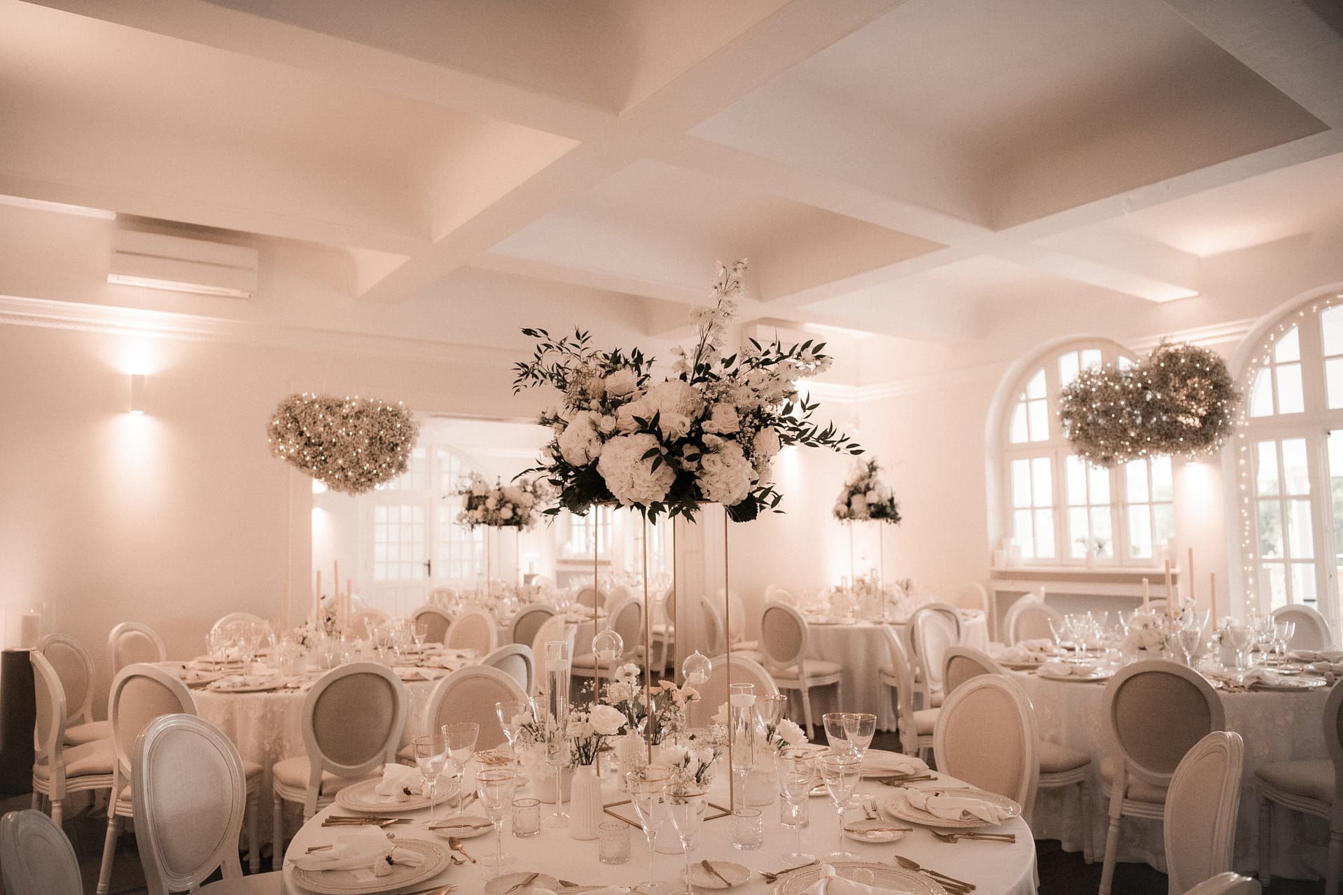 Elegante Hochzeitsfloristik mit hohen Blumengestecken Elegante Hochzeitstischdekoration mit hohen weißen Blumengestecken und schwebender Blumendekoration von Gärtnerei Reinwald Heilbronn.