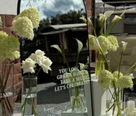 Moderner Hochzeitsspiegel mit weißer Blumendekoration aus Hortensien, Rosen und Calla.
