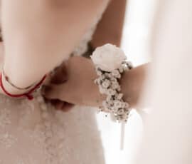 Floraler Handgelenkschmuck mit weißer Blüte und Schleierkraut am Arm der Braut.