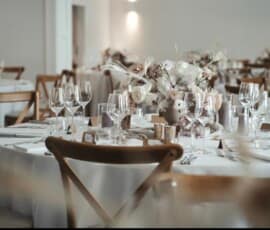 Elegante Hochzeitstafel mit weißen Blumen, Eukalyptus, Kerzen und stilvoller Tischdekoration.