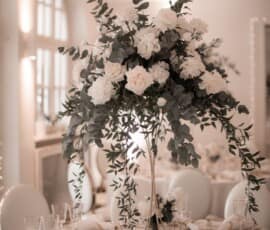 Hohe Hochzeitstischdekoration mit weißen Rosen, Blüten und Eukalyptus von Gärtnerei Reinwald Heilbronn.