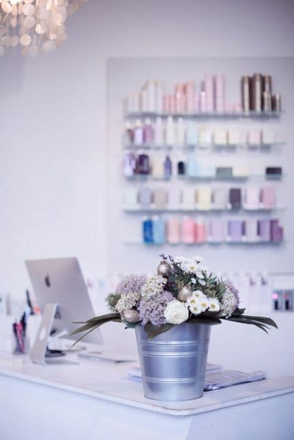 Blumenarrangement in einem silbernen Eimer mit lila und weißen Blüten sowie grünen Blättern