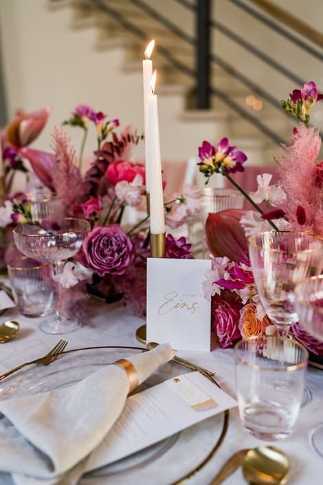Weiße Kerzen und rosa Blumenarrangement | Gärtnerei Reinwald Tischdekoration mit weißen Kerzen, rosa Blumen und Glasgefäßen