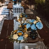 Lange Holztischtafel mit blauen Hortensien, gelben Blumen, Zitronen und gestreiften Läufern